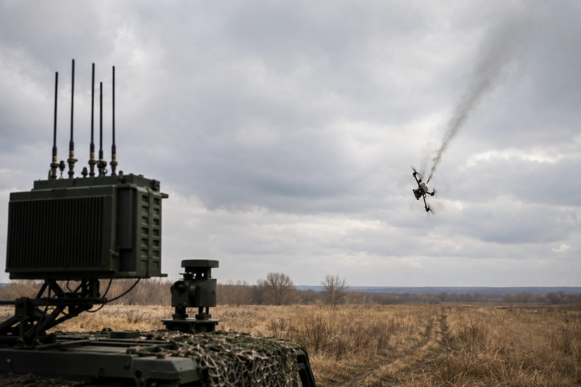 Військова станція радіоелектронної боротьби на тлі поля, поруч з якою в небо здіймається дим від дрона, що втратив управління